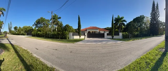 Street view of the finished property entrance with cypress and palms
