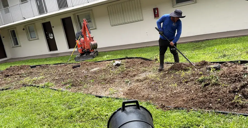 RGS crew preparing a landscape bed with a compact excavator at a multifamily property